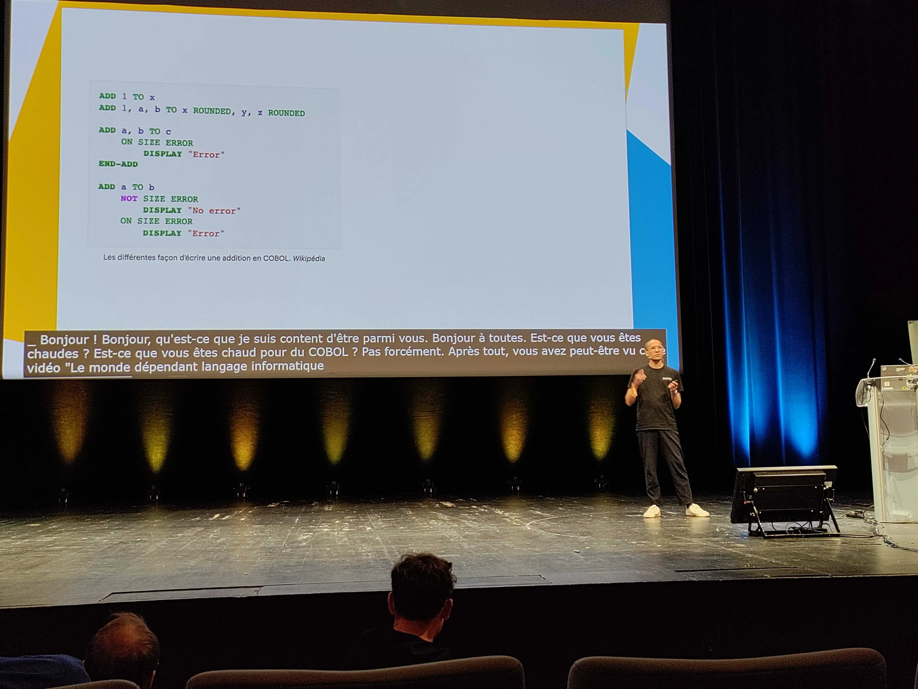 je parle sur scène à propos de COBOL. en arrière plan, du code source COBOL